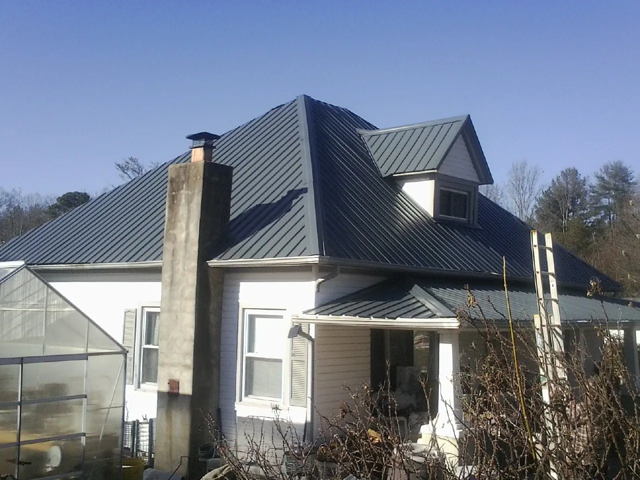 Dark blue standing seam metal roof on a white farmhouse with dormer — Slate & Tile Roof Repair by Roofing Brothers in Torrington
